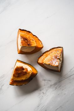 three pieces of cake sitting on top of a white counter next to another piece of fruit