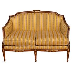 an old fashioned couch with striped upholstered fabric and wood trimming on it