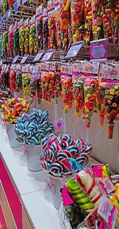 many colorful lollipops are on display at the candy stand in this store