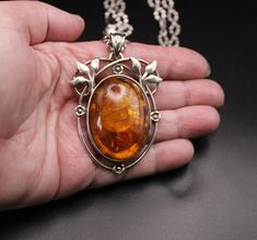 Circa 1980, a stunning amalgamation of elegance and craftsmanship emerges in this Large Solid Silver & Real Baltic Amber Oval Pendant. Set within an open-work floral mount, the radiant Baltic amber exudes warmth and intrigue, capturing the essence of nature's beauty. Crafted with precision and care, the pendant reflects the timeless allure, paired with a Solid Silver Oval Link Crimped Chain by the Italian jeweller Milor, the ensemble embodies timeless elegance and modern charm. Each link is a te Luxury Antique Amber Necklace, Luxury Amber Carved Necklace, Luxury Amber Necklaces With Large Pendant, Luxury Carved Amber Necklaces, Luxury Amber Intaglio Jewelry, Vintage Oval Necklace With Polished Finish, Vintage Oval Necklaces With Polished Finish, Vintage Hallmarked Oval Cabochon Necklace, Collectible Oval Amber Necklaces