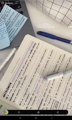 an open notebook sitting on top of a desk next to a laptop computer and pen