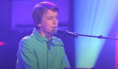 a young boy sitting at a piano in front of a microphone