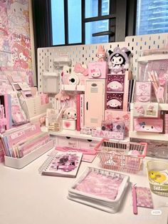 there are many pink items on the counter in this office space, including pens and notebooks