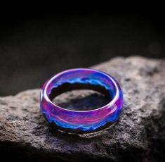 a purple and blue ring sitting on top of a rock