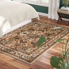 a large rug on the floor in a room with green walls and hardwood floors, along with a bed