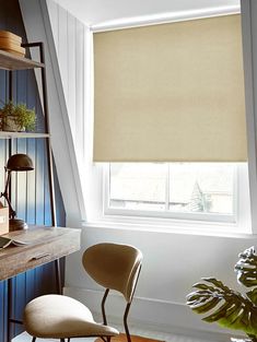 a room with a desk, chair and window that has a roller shade on it