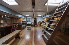 a large room with wooden floors and lots of furniture on the walls, along with a staircase leading up to an open floor plan