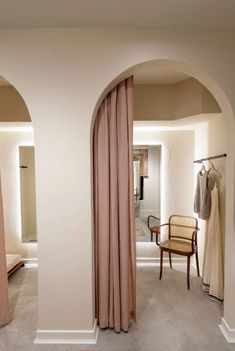 an arched doorway leads into a bedroom with beige curtains