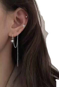 a woman wearing silver earrings with stars and chains hanging from the back of her ear