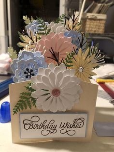 a birthday card with flowers in it sitting on a table