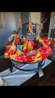 an arrangement of paper flowers in a glass bowl on a table with a sign behind it