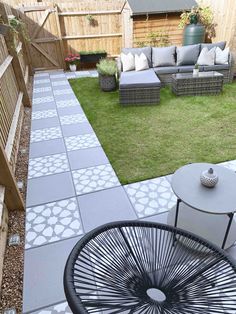 an outdoor patio area with chairs and tables in the grass, next to a wooden fence