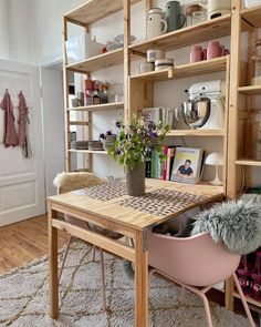 a wooden table sitting in front of a book shelf filled with books and vases