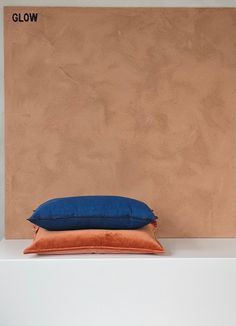 a blue pillow sitting on top of a white shelf next to a brown and tan wall