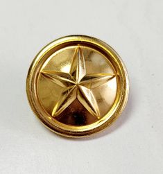 a gold colored metal button with a star on the center and two holes in the middle