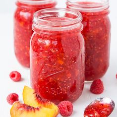 raspberry peach freeze jam in mason jars with spoons and fresh fruit on the side