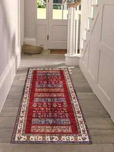 a red rug is on the ground in front of a door and stairs with white trim