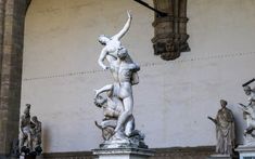 several statues in front of a building with columns