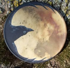 a black bird painted on the side of a brown and black plate next to a tree