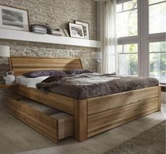 a large bed with drawers underneath it in a living room next to a brick wall