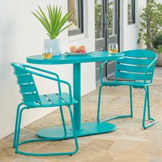 a blue table and two chairs sitting on top of a tile floor next to a potted plant