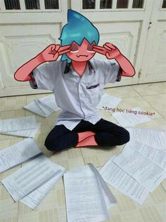 a person sitting on the floor with papers all around him and covering their eyes in front of them