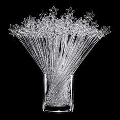 a glass vase filled with lots of flowers on top of a black background, in the shape of stars