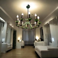 a chandelier hanging from the ceiling in a room with couches and tables