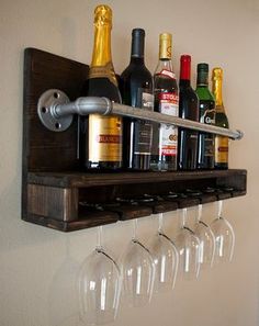 wine glasses and bottles are lined up on a wooden shelf with a metal bar handle