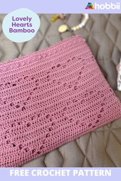 a pink crocheted blanket sitting on top of a bed with the words lovely hearts bamboo