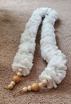 two pieces of white fabric and wooden beads on the floor next to eachother