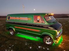 an old green van is parked in the grass with its lights on and it's door open