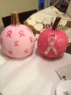 two pumpkins decorated with pink ribbon and ribbons are sitting on a table next to each other