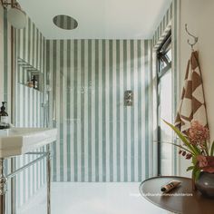 a bathroom with striped walls and flooring next to a sink, toilet and shower