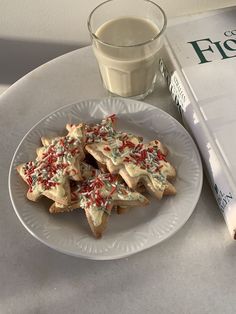 a white plate topped with cut up cookies next to a glass of milk and a book