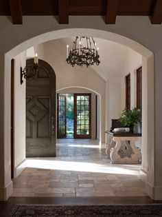 an archway leading to a foyer with a chandelier hanging from it's ceiling