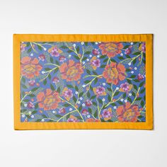 an orange and blue floral print scarf on a white background with yellow border around the edges