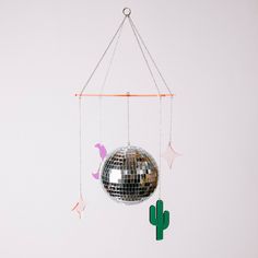 a silver disco ball hanging from a chain next to a cactus and star shaped object