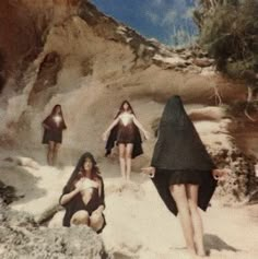 four women dressed in black and white are walking through the desert