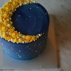 a blue cake with yellow flowers on it's top and the moon in the middle