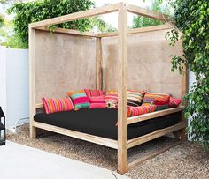 a bed sitting in the middle of a yard with pillows on it's sides