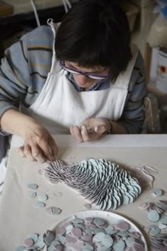 a woman is working on an art project with buttons and paper machs in front of her