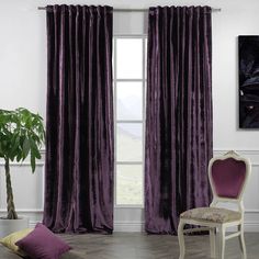 a chair sitting in front of a window covered in purple velvet curtains and matching throw pillows