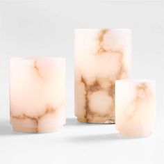 three marbled candles sitting next to each other on a white surface with one candle in the middle