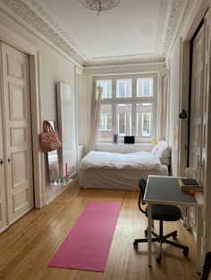 a bedroom with a bed, desk and chair in it next to a large window