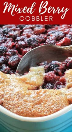 mixed berry cobbler in a blue casserole dish with a spoon scooping out