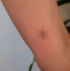 a small snowflake tattoo on the arm