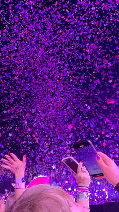 two people holding their cell phones in front of confetti falling from the ceiling