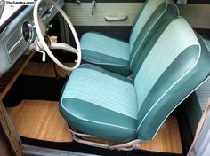 the interior of an old car with wood flooring and blue leather upholstered seats