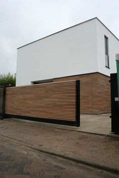 a large white building sitting on the side of a road next to a tall wooden fence